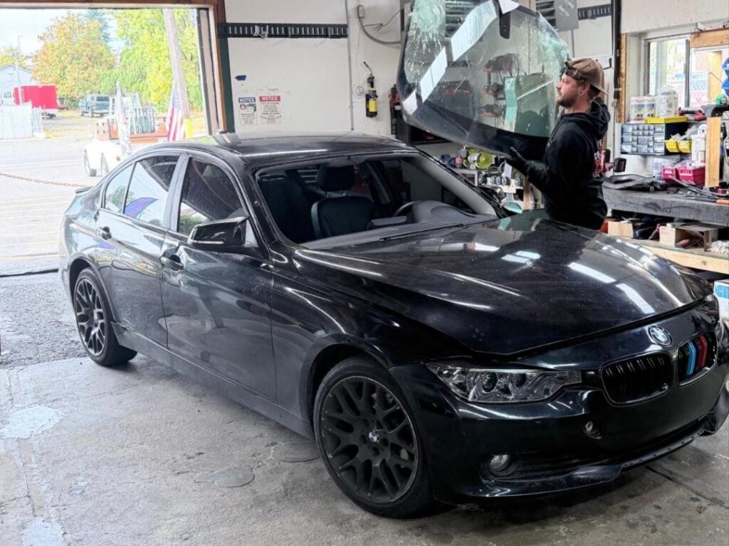 Technicians lifting out a shattered BMW windshield during replacement in Bremerton